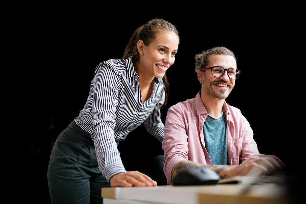 2 Bürofachkräfte schauen gemeinsam auf einen Monitor 