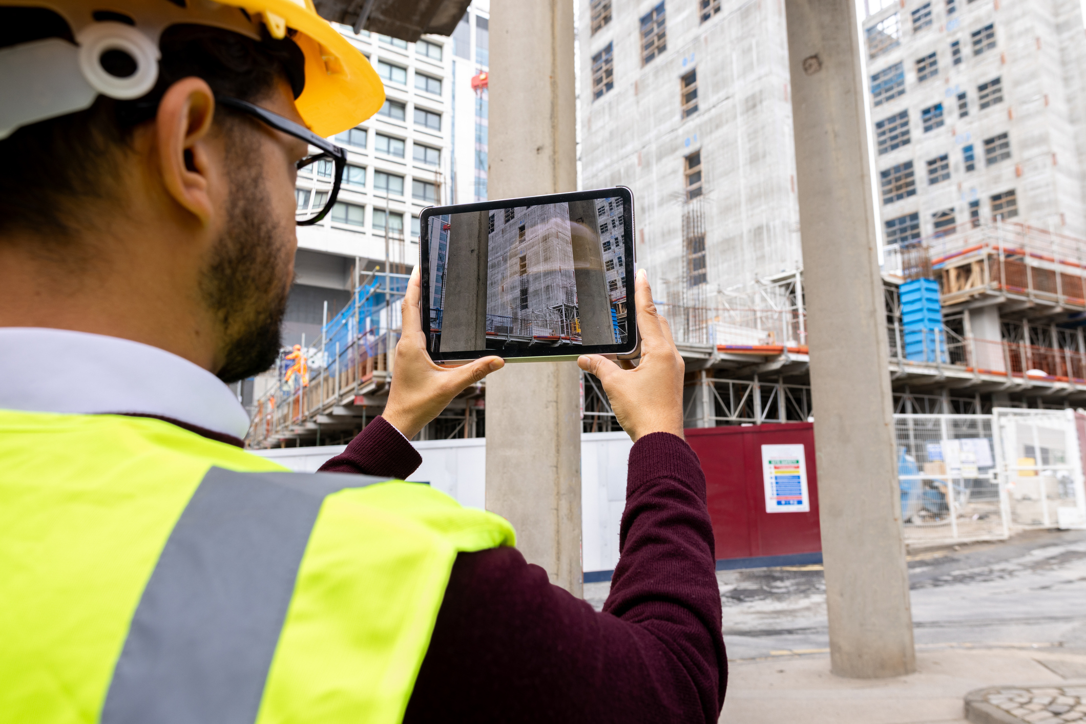 Ein Mann schaut auf ein Tablet auf einer Baustelle